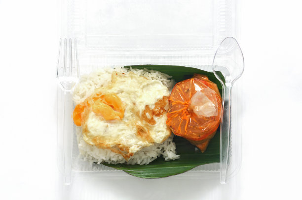 茉莉花饭配咖喱猪肉和煎蛋，装在透明的塑料盒子里，底部放上香蕉叶，就可以吃了图片下载