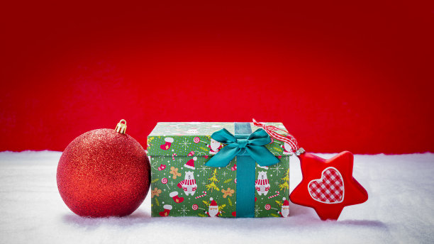 在雪地里装着圣诞树球和一品红的圣诞包图片下载