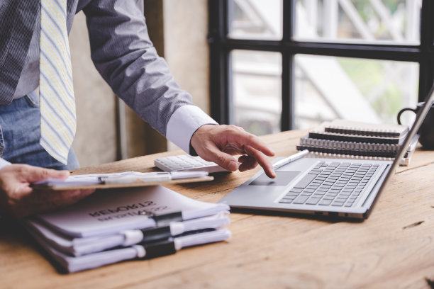 在办公室工作一个商人在家的桌子上处理一堆文件来寻找信息。商务报告一堆未完成的文件图片下载