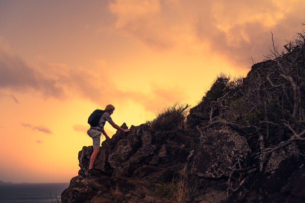 成熟的男人爬上山顶。图片下载