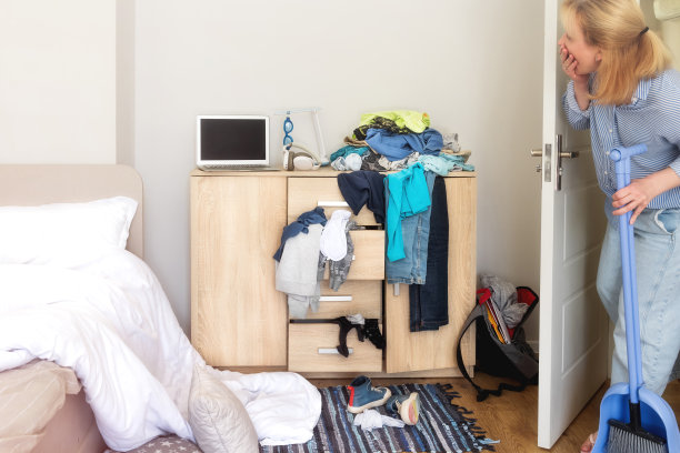 一个女人走进一个十几岁的孩子凌乱的房间打扫，她对房间的凌乱感到惊讶图片下载