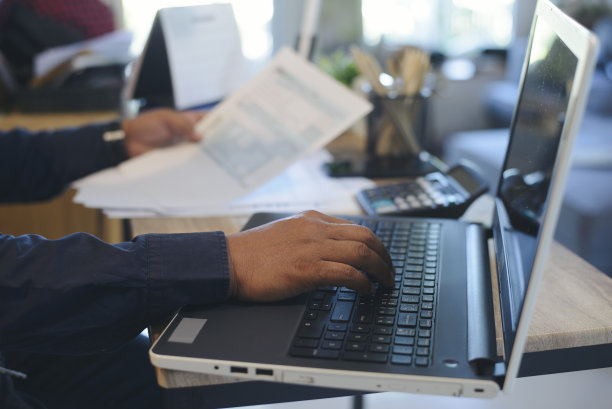 具备纳税季、预算和纳税筹划的概念。商人汉德用手机计算年税。计算器，日历2023和个人所得税表格放在家庭办公室的桌子上。图片下载