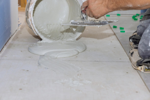 在铺设地砖的准备工作中，抹灰砂浆将粘合剂涂在混凝土地板上图片下载