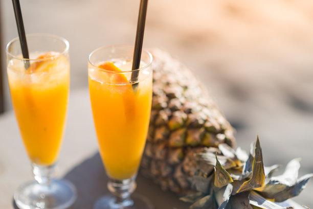 菠萝和黄色新鲜和冷鸡尾酒在热带海滩，库存照片图片下载