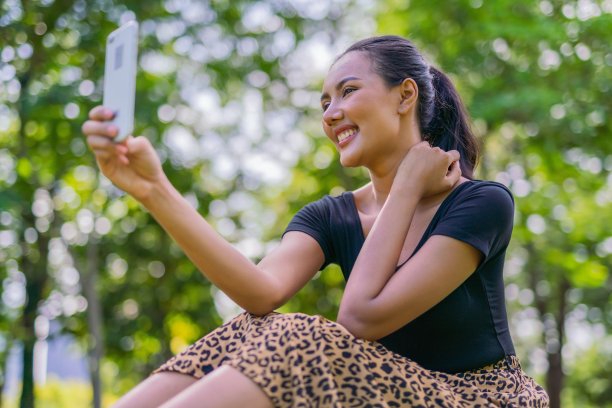 一个美丽的和好看的年轻亚洲女性模特女士穿着夏天的冷连衣裙在公园讲手机图片下载
