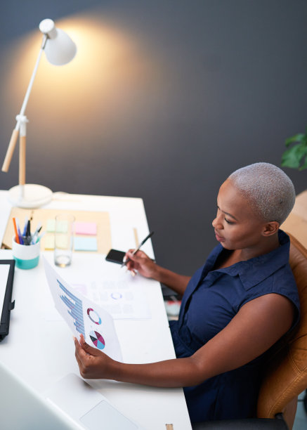 一个年轻的黑人女商人在深夜读一份财务报告图片下载