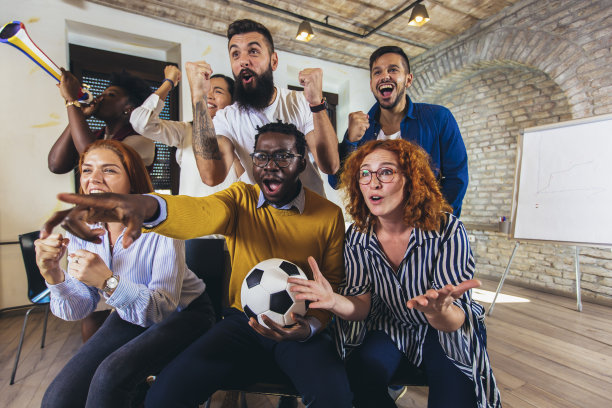 快乐的休闲商务人士或在电视上观看足球比赛庆祝胜利的球迷。友谊、体育、娱乐理念。图片下载