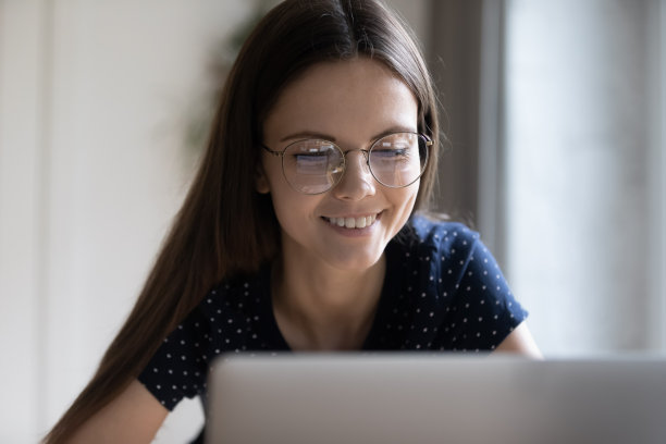 聪明的女学生戴着眼镜在家学习，用电脑图片下载