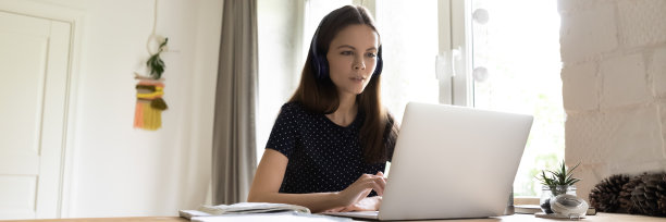 专注的女生戴着无线耳机观看学习视频教程图片下载