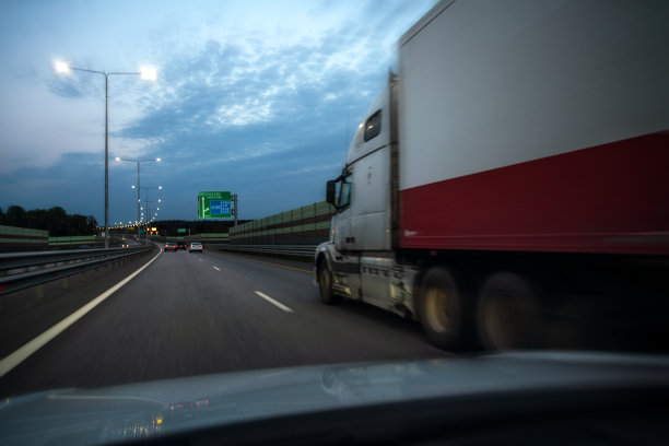大半卡车在高速公路上的傍晚，从最近的车看图片下载