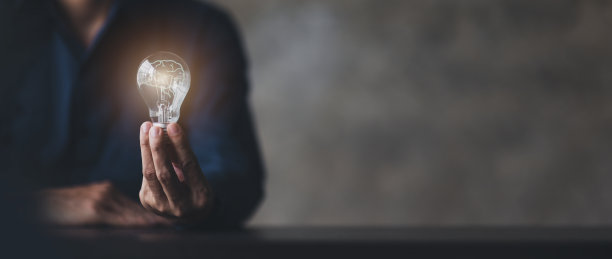 商人拿着一盏发光的灯，创造新的想法。创新，头脑风暴，灵感和解决方案的概念。这个人拿着灯泡。空间背景副本。图片下载
