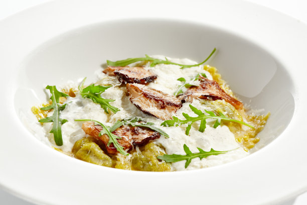 蘑菇馄饨和芝士酱在白色背景上分离。意大利菜-白色盘子上的意式馄饨配牛肝菌和奶油espuma。餐厅菜品配野生菌。图片下载