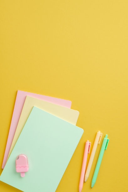 回到学校概念。俯视图垂直照片的彩色学校配件堆叠笔记本冰淇淋形状的卷笔刀和钢笔在孤立的黄色背景与copyspace图片下载