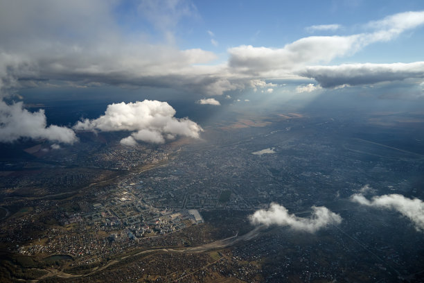 在暴风雨来临前，远处的城市在高空被膨胀的积云覆盖的飞机窗口鸟瞰图图片下载