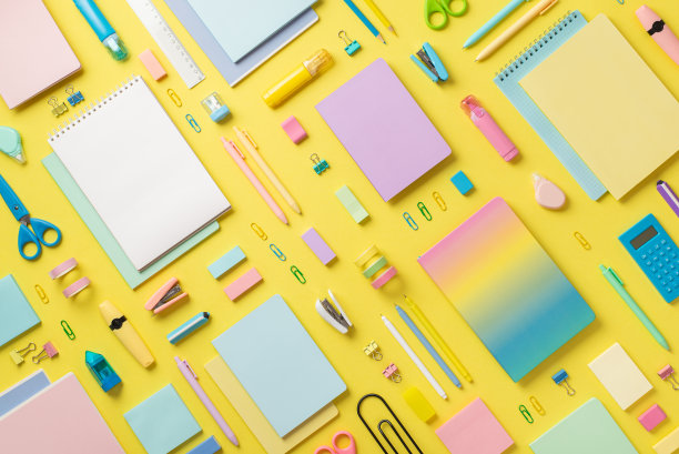 彩色文具笔记本铅笔校正笔记号笔夹子订书机计算器尺子胶带剪刀磨刀器橡皮擦在孤立的黄色背景上的便签纸的俯视图照片图片下载