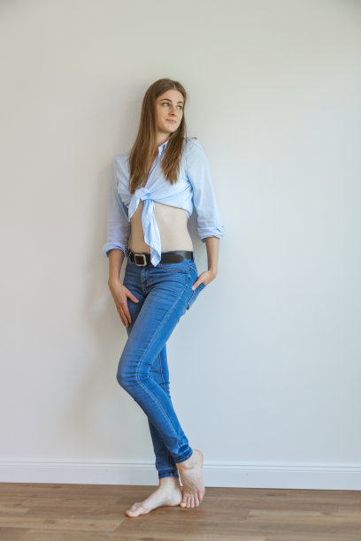 一个穿着牛仔裤和蓝色衬衫的美丽年轻女人的完整肖像。身体积极的。幸运的人。图片下载