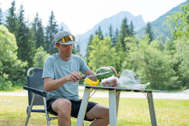 一个人在露营地的野餐桌上切水果图片下载