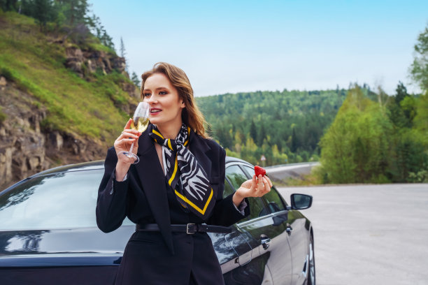 年轻漂亮的女人拿着酒站在车旁图片下载