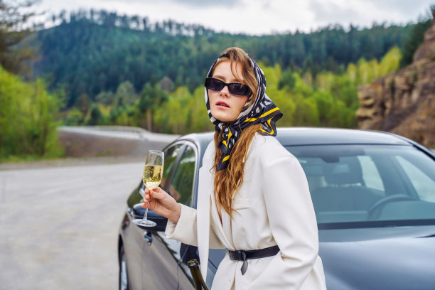 年轻漂亮的女人拿着酒站在车旁图片下载
