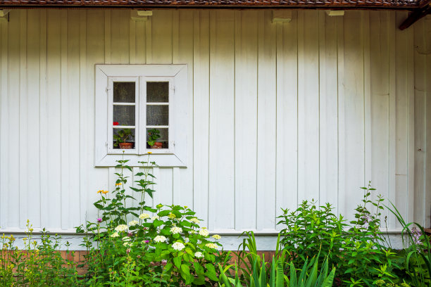 老房子正面的照片。白色的漆板。一个小窗户和一个美丽的小花园图片下载