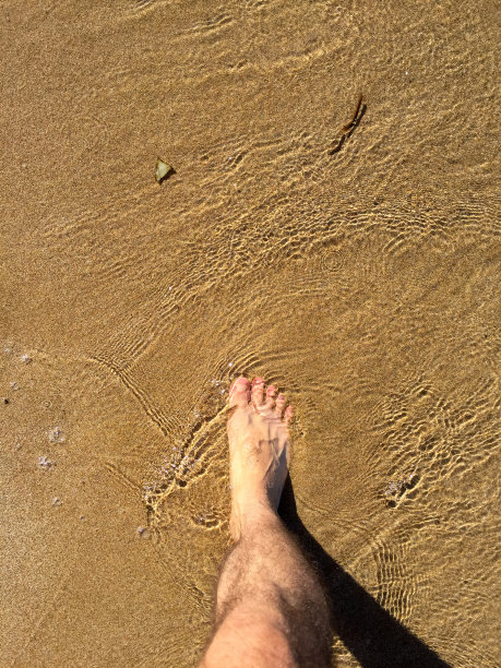 走在沙滩上，人的脚踩在带着波浪的沙滩上图片下载