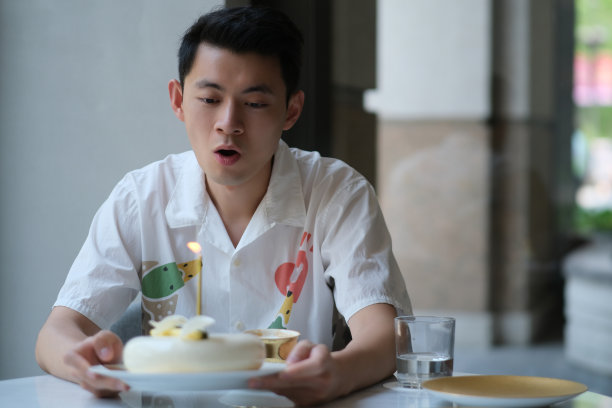 年轻男人吹生日蛋糕上的蜡烛图片下载
