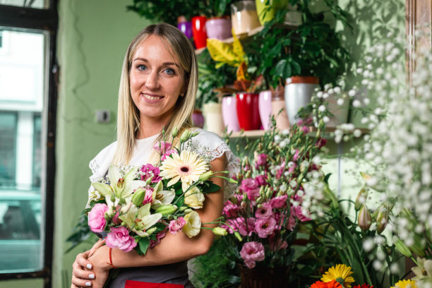 美丽的女孩在花店工作。进行装饰和布置。送花，创造秩序。小生意。图片下载