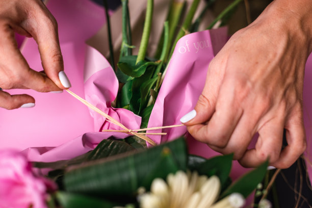 人，园艺和花卉设计概念-从上到下特写的女人或花卉艺术家制作一束花，并在工作室的桌子上系蝴蝶结图片下载