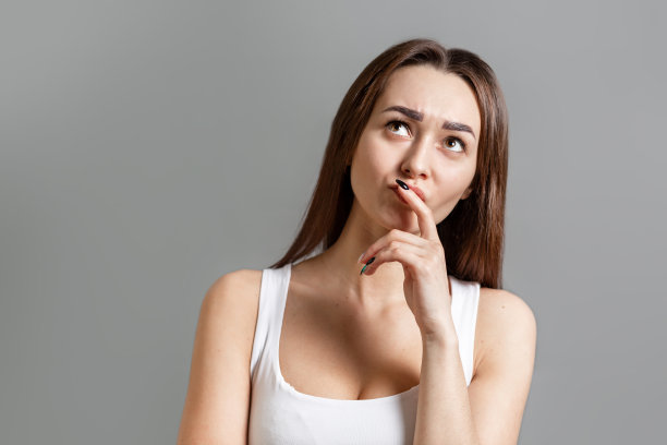 概念的想法和信息搜索。一个忧郁的年轻白人女人的肖像，她皱着眉头向上看。灰色的背景。本空间图片下载