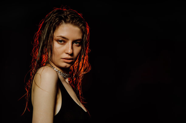 我不相信你。悲观不满的女人看着相机从额头下，摆出黑色背景，一个年轻女人的情感肖像图片下载