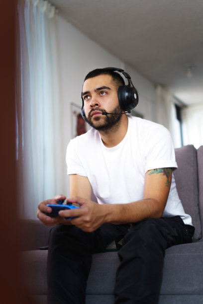 留着黑色头发和胡子的男人拿着游戏机控制器和仪表，是游戏玩家的生活方式图片下载