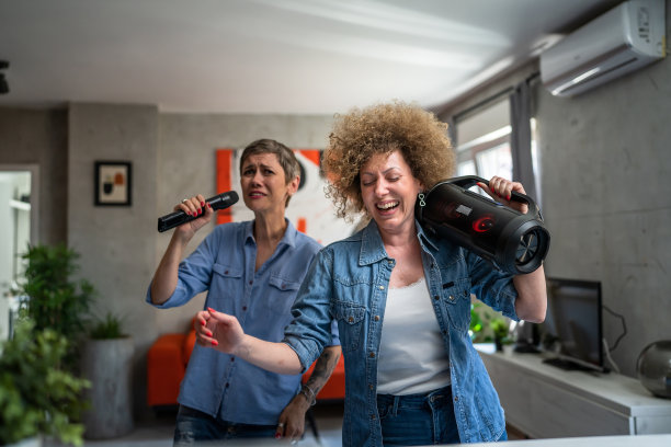 两个女人成年成熟的白人朋友或姐妹在家里玩女性跳舞和唱歌卡拉ok拿着麦克风听音乐快乐的微笑快乐的节奏真实的人复制空间图片下载