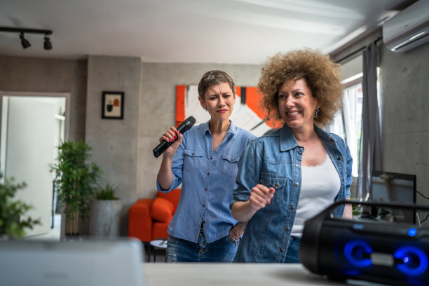 两个女人成年成熟的白人朋友或姐妹在家里玩女性跳舞和唱歌卡拉ok拿着麦克风听音乐快乐的微笑快乐的节奏真实的人复制空间图片下载