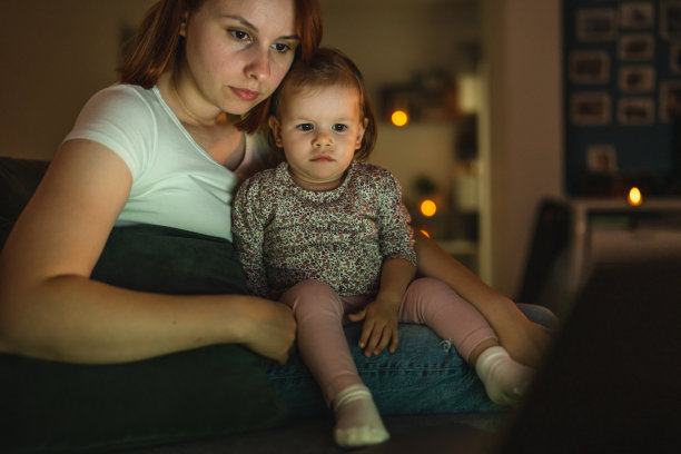 小白人孩子小女孩蹒跚学步的母亲和女儿坐在黑暗的房间，晚上在家里的沙发床上看卡通或电影在笔记本电脑真人家庭成长的拷贝空间图片下载