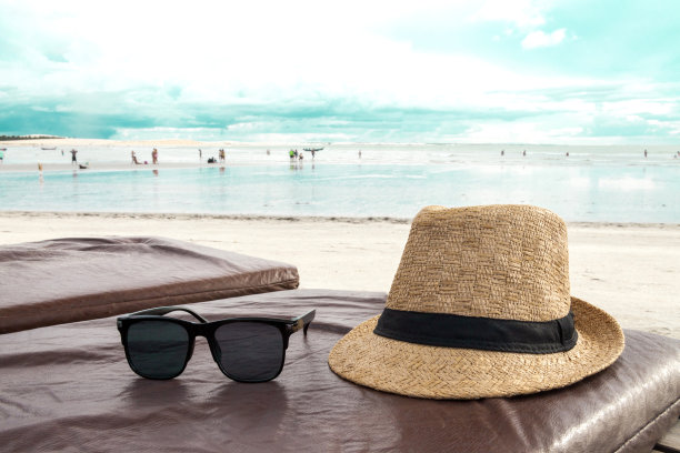 沙滩椅上戴着帽子和墨镜，背景是大海和蓝天。巴西海滩。图片下载