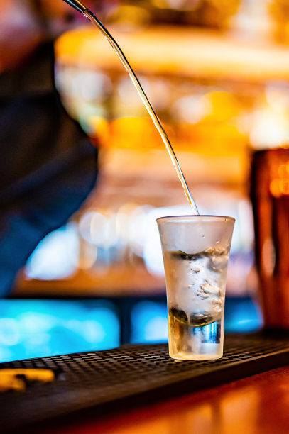 酒吧里把蒸馏酒倒入小酒杯的酒保图片下载