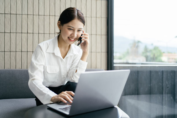 亚洲商业女性在办公室穿着正式的西装愉快地使用智能手机和工作。图片下载