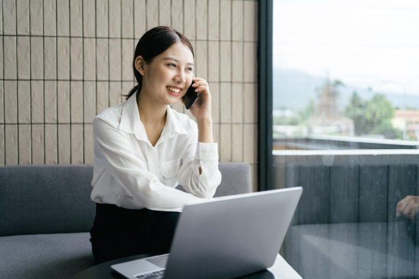 亚洲商业女性在办公室穿着正式的西装愉快地使用智能手机和工作。图片下载