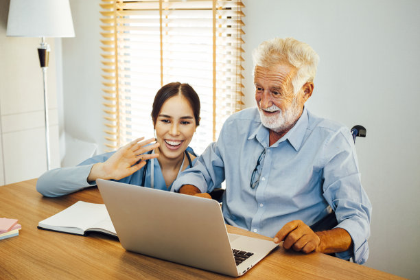一位年长的商人在护士的监督下进行视频会议。图片下载