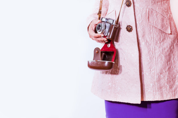 身穿淡粉色外套的女子手持复古相机。孤立在白色背景。图片下载