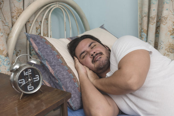 一个留着胡子的混血男子在他公寓的床上侧卧着睡得很香。快速眼动睡眠。图片下载