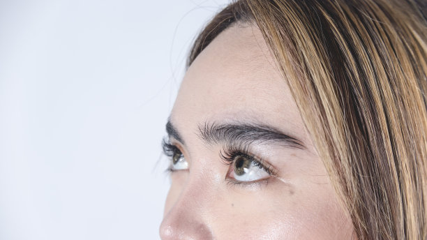 一个20多岁的菲律宾女人的前额和眼睛的特写。长睫毛，戴琥珀色隐形眼镜。图片下载