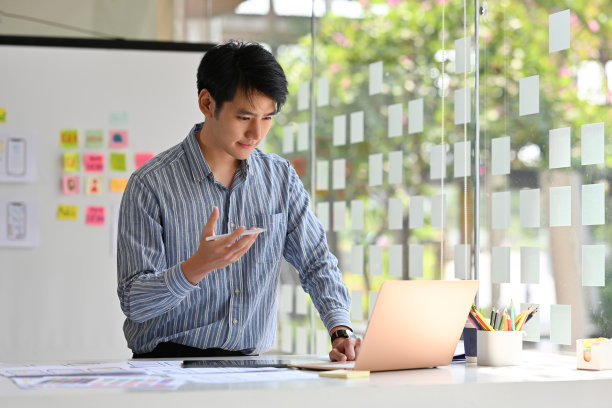 年轻的亚洲男性用户体验设计师，在办公室工作的笔记本电脑，网站设计师，创意规划手机应用开发模板布局框架，用户体验概念。图片下载