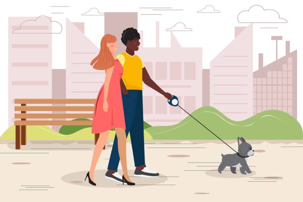 一对年轻的夫妇在城市公园遛狗。图片下载