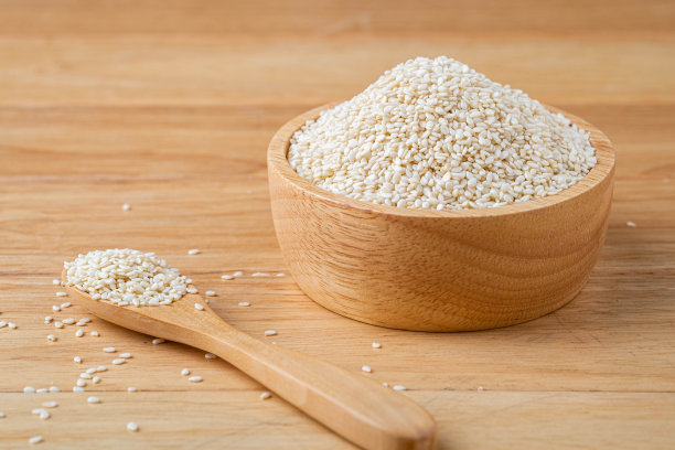 白芝麻放在木勺和木碗里放在桌上，有机食品的概念。图片下载