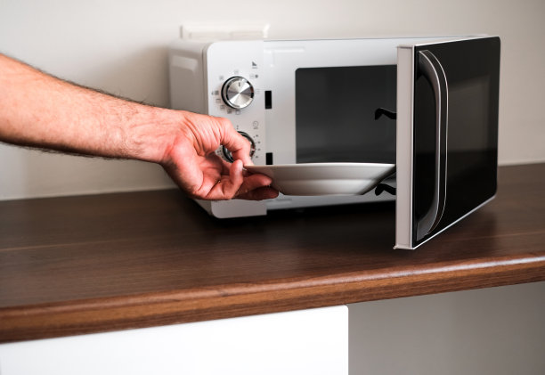 男人打开微波炉拿他的盘子里的食物图片下载