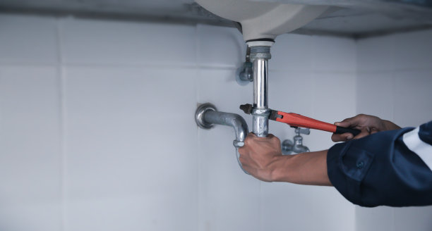 男管道工用扳手修理家庭浴室漏水的水槽。图片下载