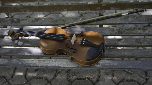小提琴和琴弓放在公园里一把生锈的旧椅子上，图片下载