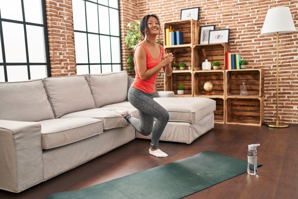 年轻的中国女性微笑着自信地训练腿部运动在家里图片下载