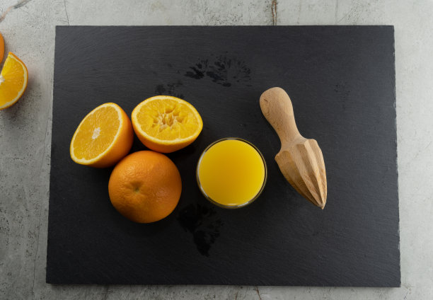 新鲜成熟的橘子和果汁在黑色石板，大理石石背景。前视图中,挤压。图片下载